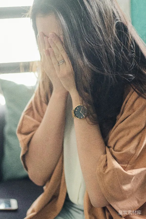 穿着棕色上衣的女人捂住脸