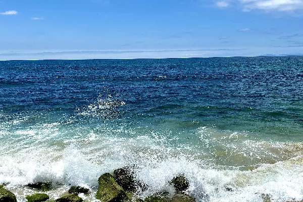 高清摄影 海浪在蓝天白云下白天撞击岩石的景象