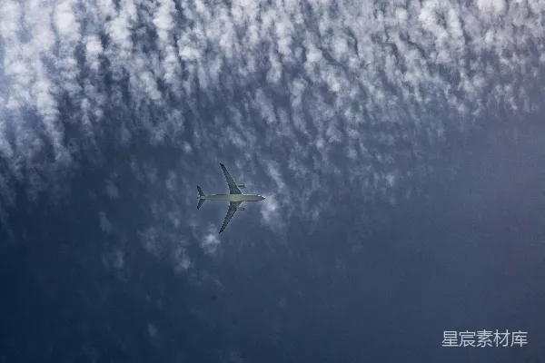 高清摄影 空中飞机在蓝色的天空中飞过纹理状的云层。