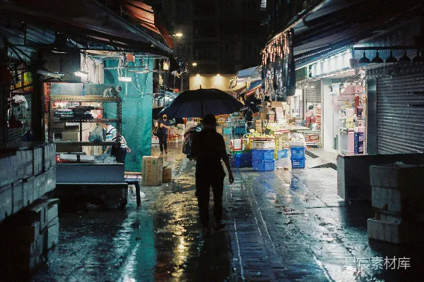 高清摄影 手持雨伞的人在夜晚走在湿漉漉的街道上。