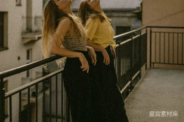 高清摄影 两位妇女抬头看着，一白一倚靠在栅栏上