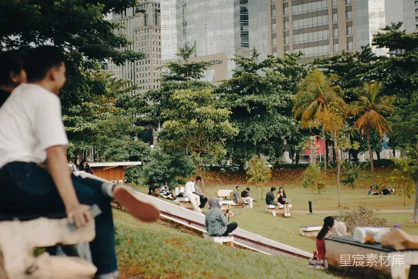 高清摄影 一群人在一片浓绿的公园顶部坐著。