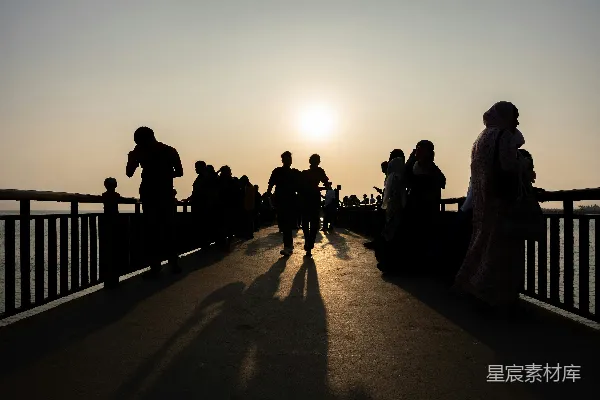 高清摄影 夕阳下，人群在桥上的 silhouette。