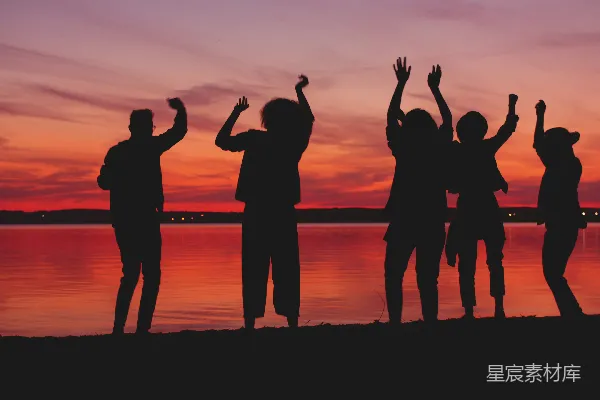 高清摄影 夕阳下，人们 dancing 的轮廓映衬在水边。
