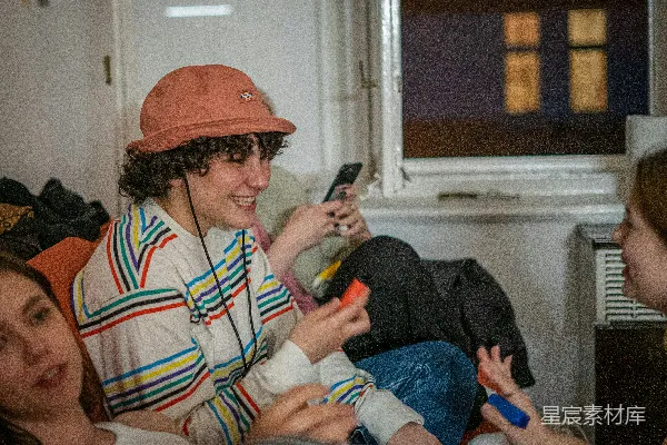高清摄影 一群人在沙发上坐着，手里拿着手机。
