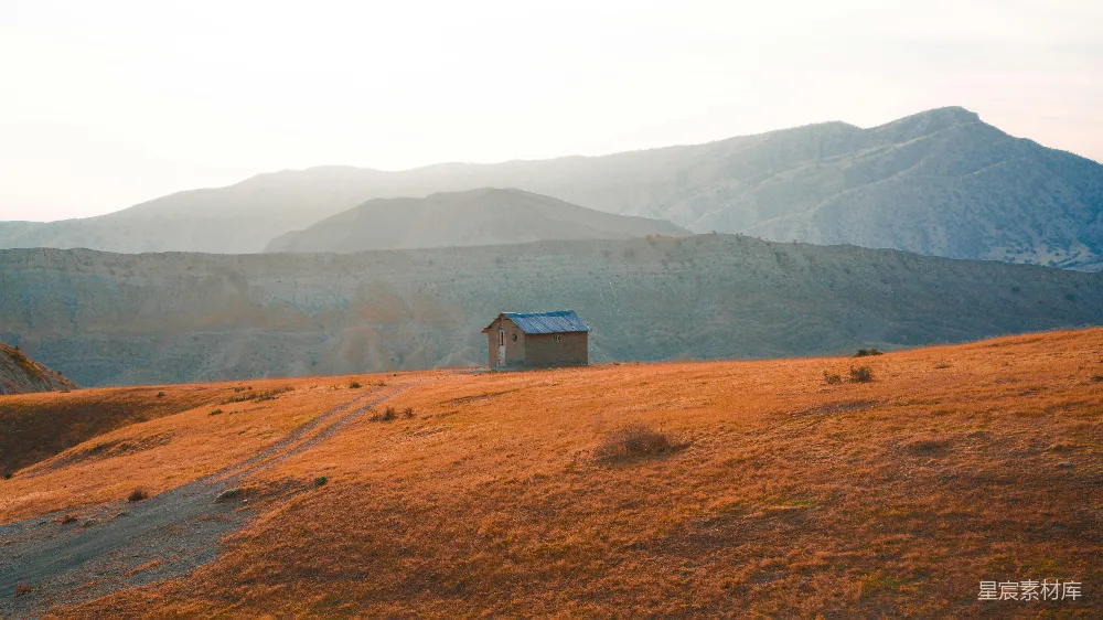 高清摄影 山坡上的一所小屋，背景是山峦。