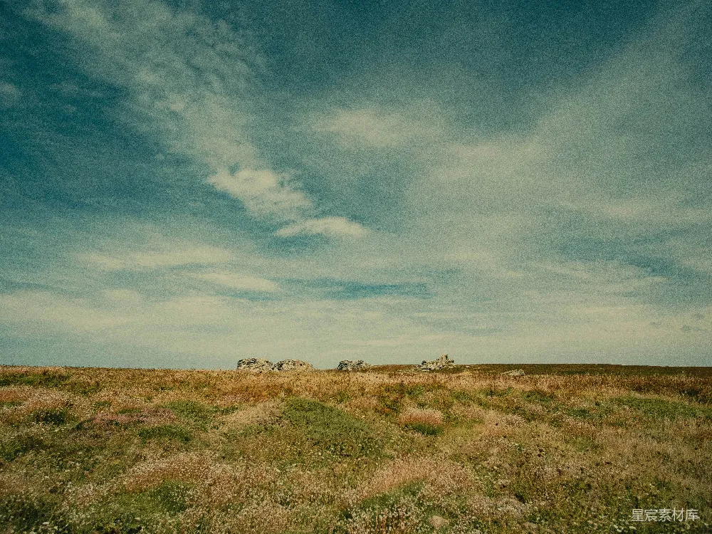 高清摄影 远处有一片草地，几块石头在其中。