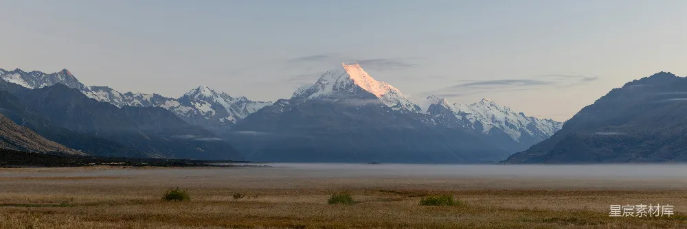 高清摄影 皑皑山峰在晨雾平原上沐浴着初升的太阳光辉。
