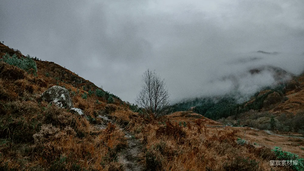 高清摄影 山坡上一条尘土路，在背景中有层云的天空中。