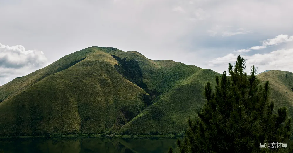 高清摄影  一座山峦前方有一片水域。
