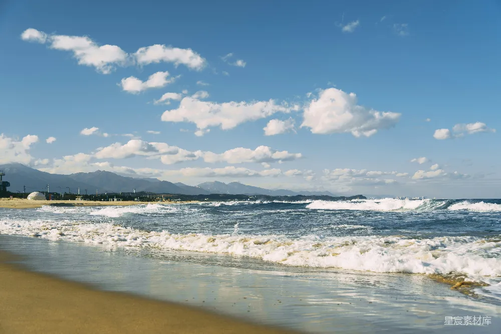 高清摄影 一片沙滩，海浪涌向岸边。