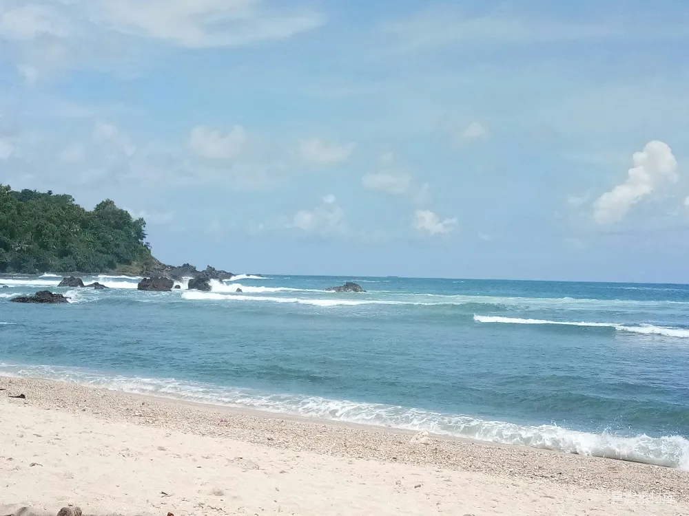 高清摄影  一片沙子覆盖的海滩，波浪涌向岸边。