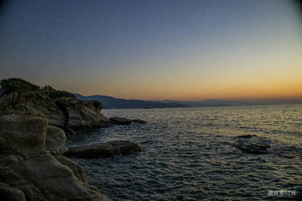 高清摄影 夕阳西下，海天相接处有一块岩石突兀。
