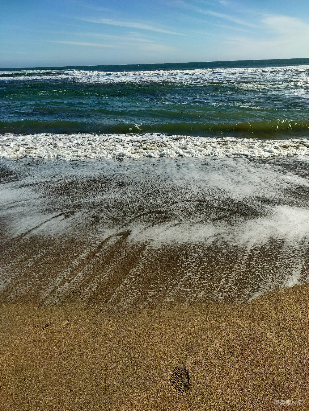 高清摄影 一片沙子覆盖的海滩，海水时而涌进，时而出现。