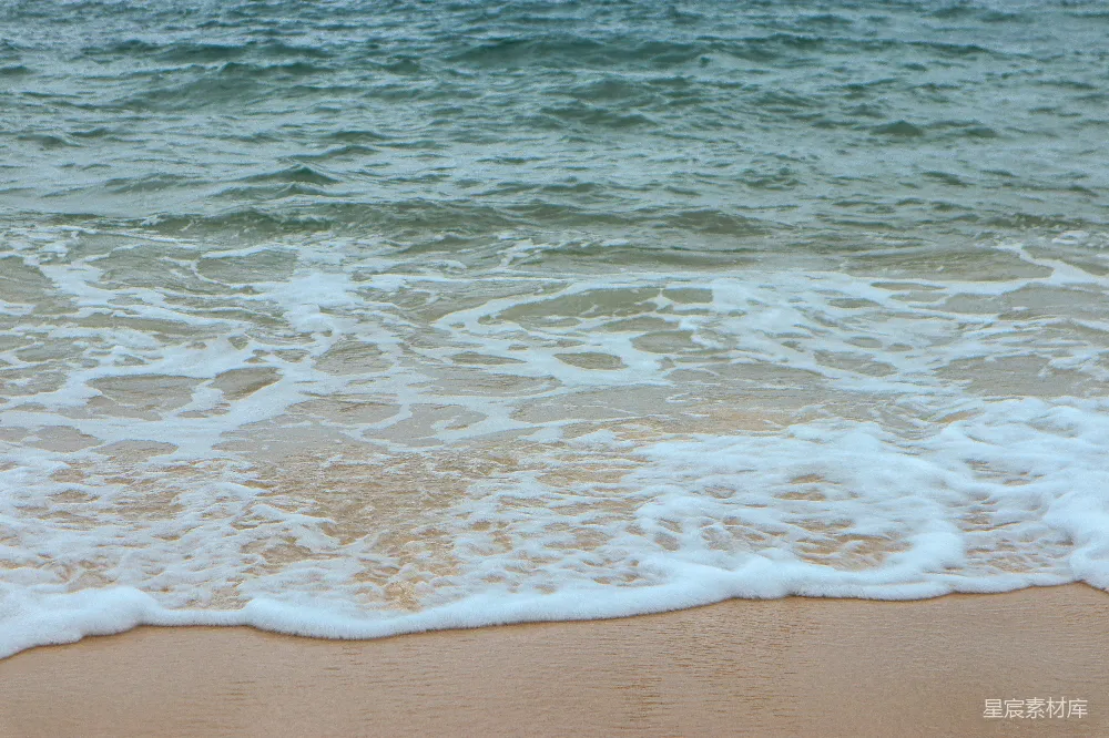 高清摄影 一片沙子覆盖的海滩，海浪涌向岸边。