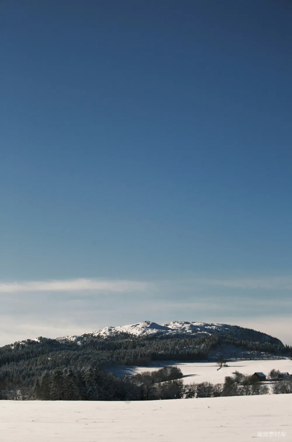 高清摄影 覆盖着白雪的田野，在背景中有一座山峰。