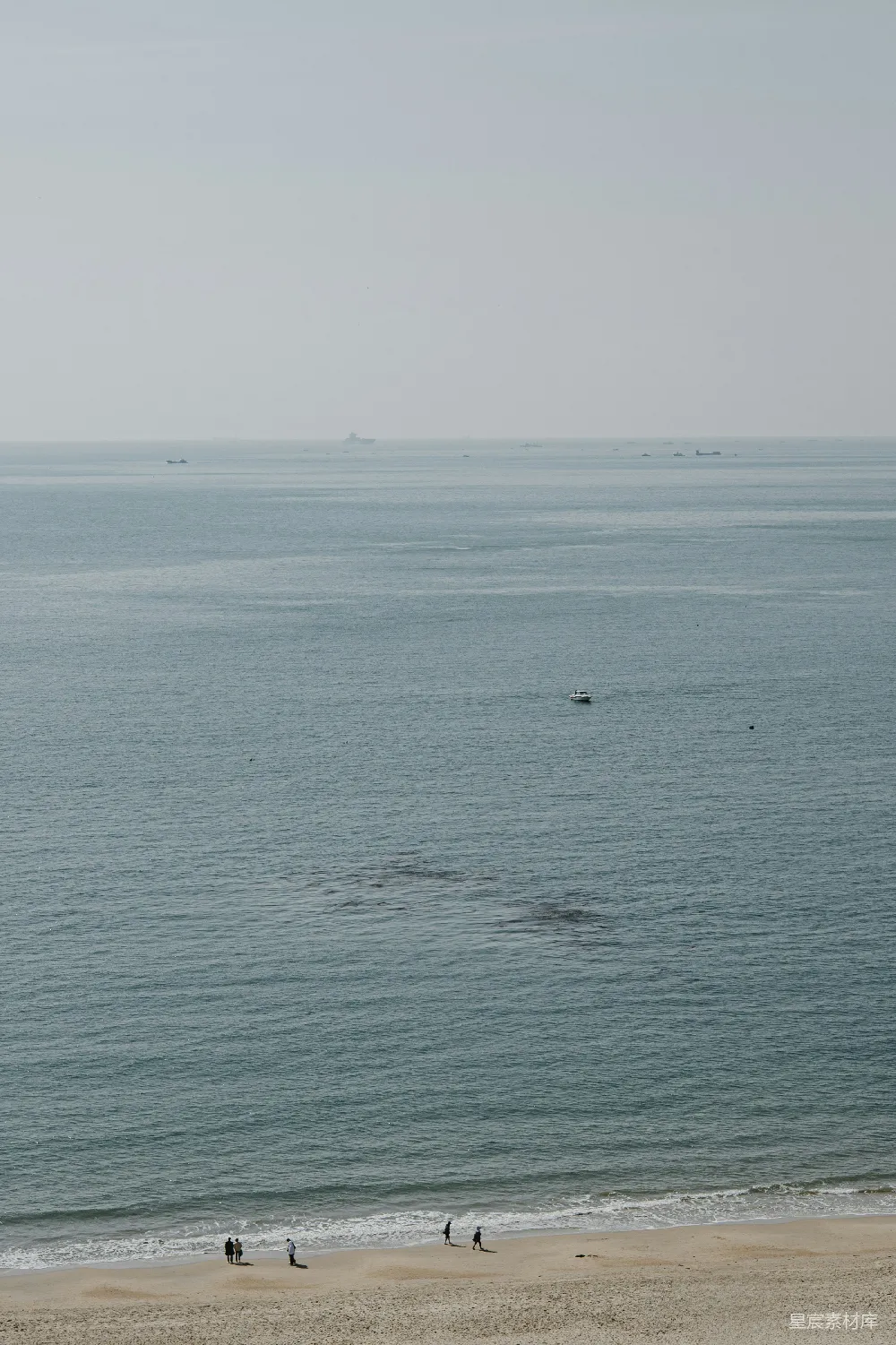 高清摄影 人们在海滩上漫步，眺望着海洋。