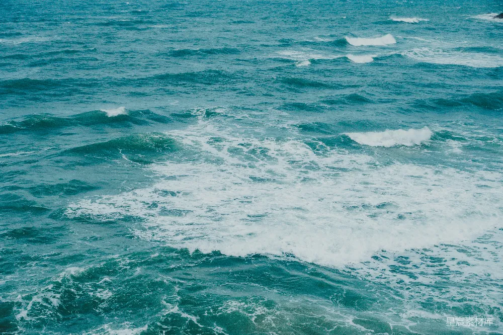 高清摄影  波涛在广阔的蓝色海洋中拍打翻腾，泛起泡沫。