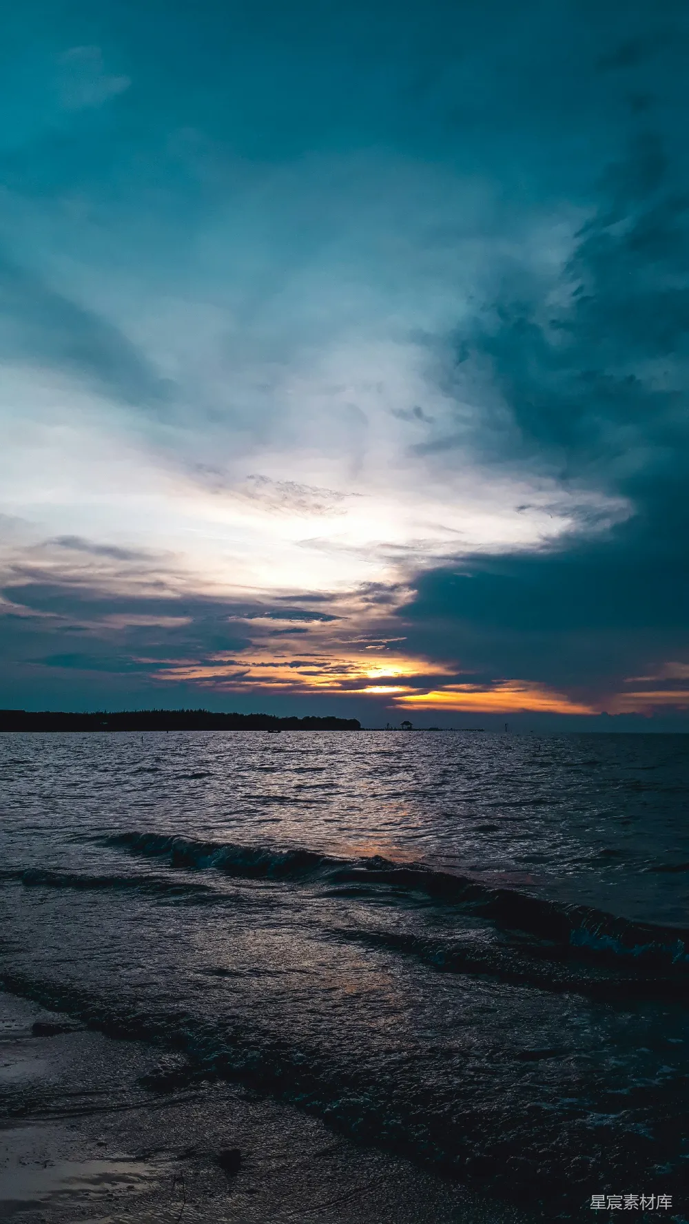 高清摄影  夕阳下波光粼粼的海浪在阴云密布的天空中