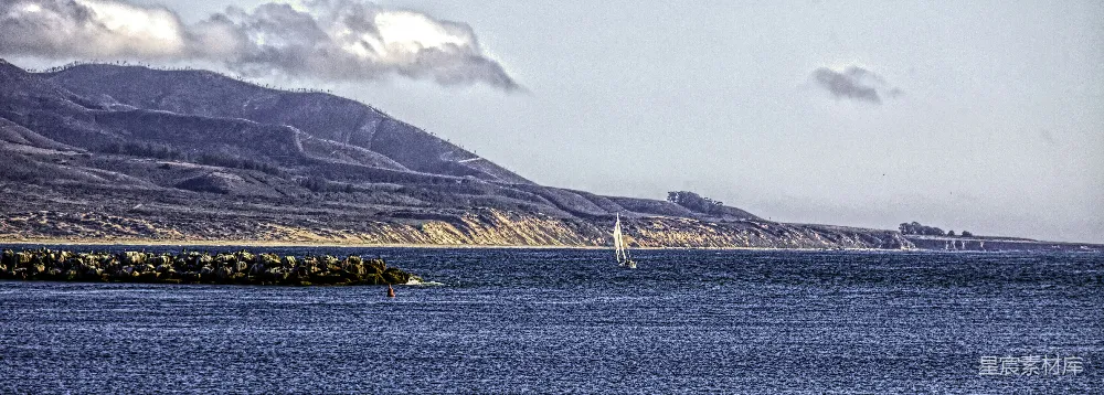 高清摄影 一艘帆船近旁有一座山正漂浮在水面上。