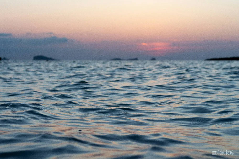 高清摄影 在日落时分平息海浪，远处岛屿隐约可见