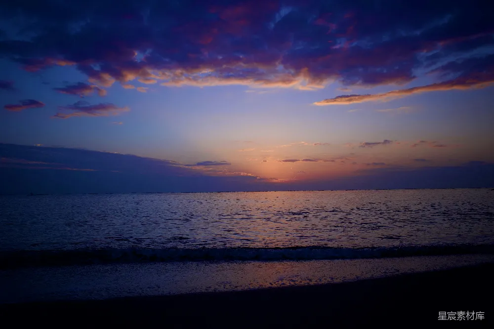 高清摄影 海滩上的水边正落下夕阳。
