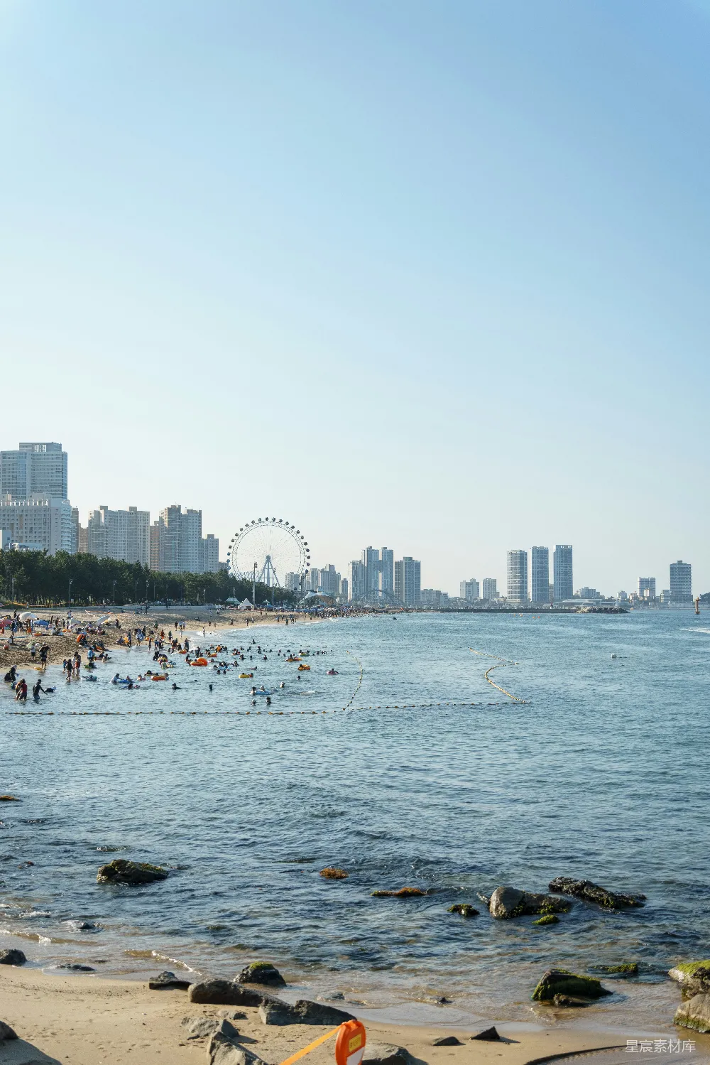 高清摄影 海滩上人声鼎沸，背景中有摩天轮。