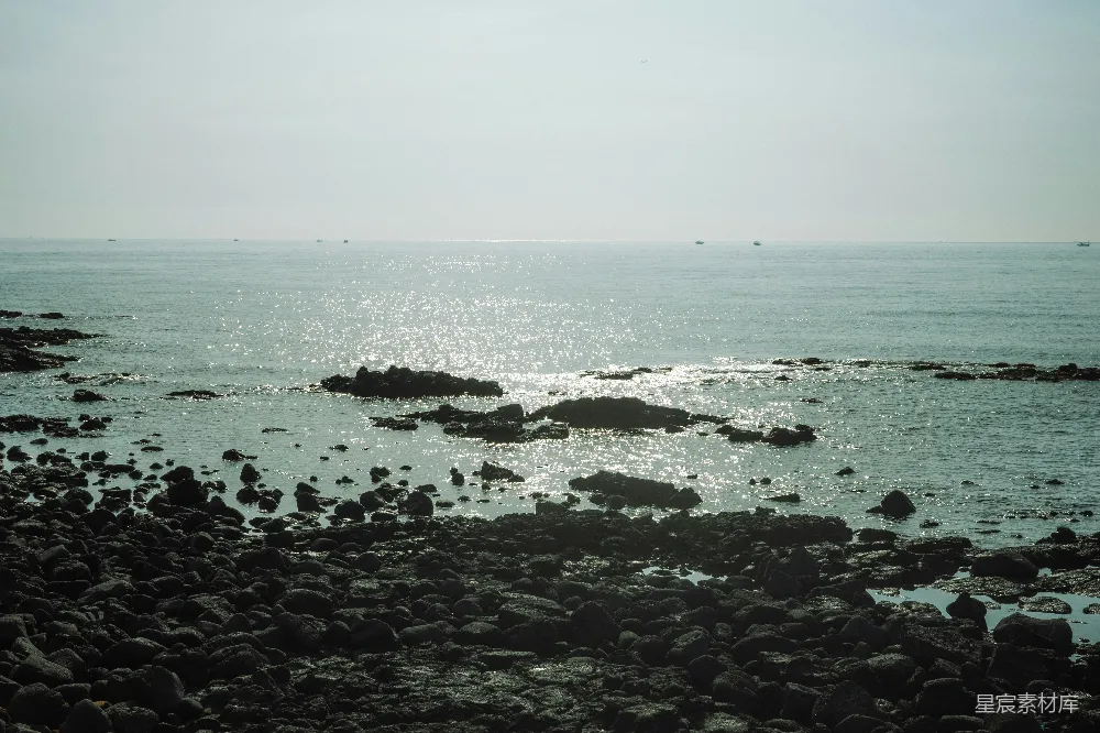 高清摄影 岩石海岸与平静闪耀的海洋水相遇。