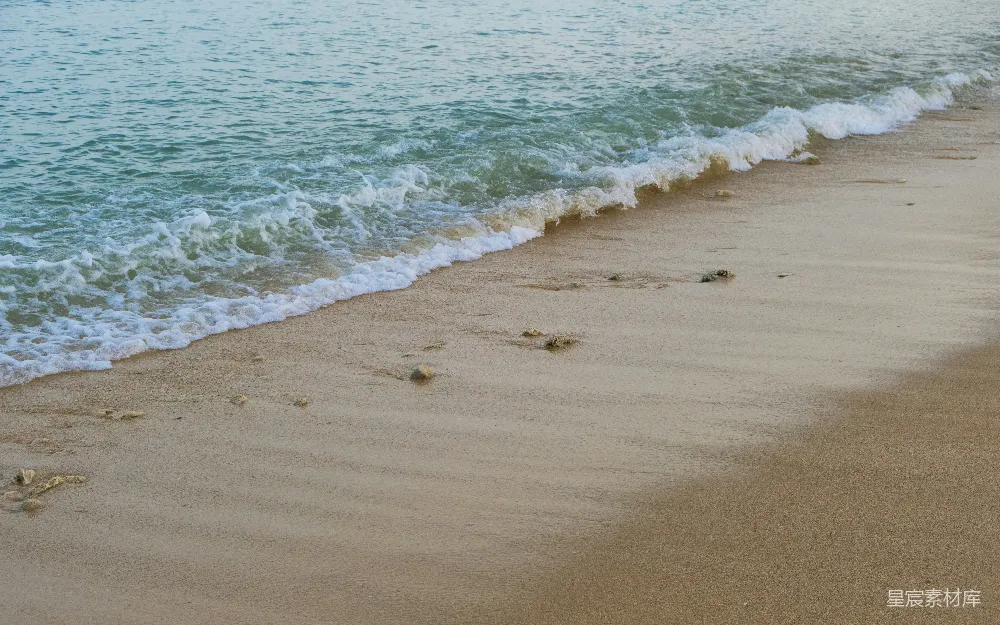 高清摄影  一片沙白的海滩，海浪涌向岸边。