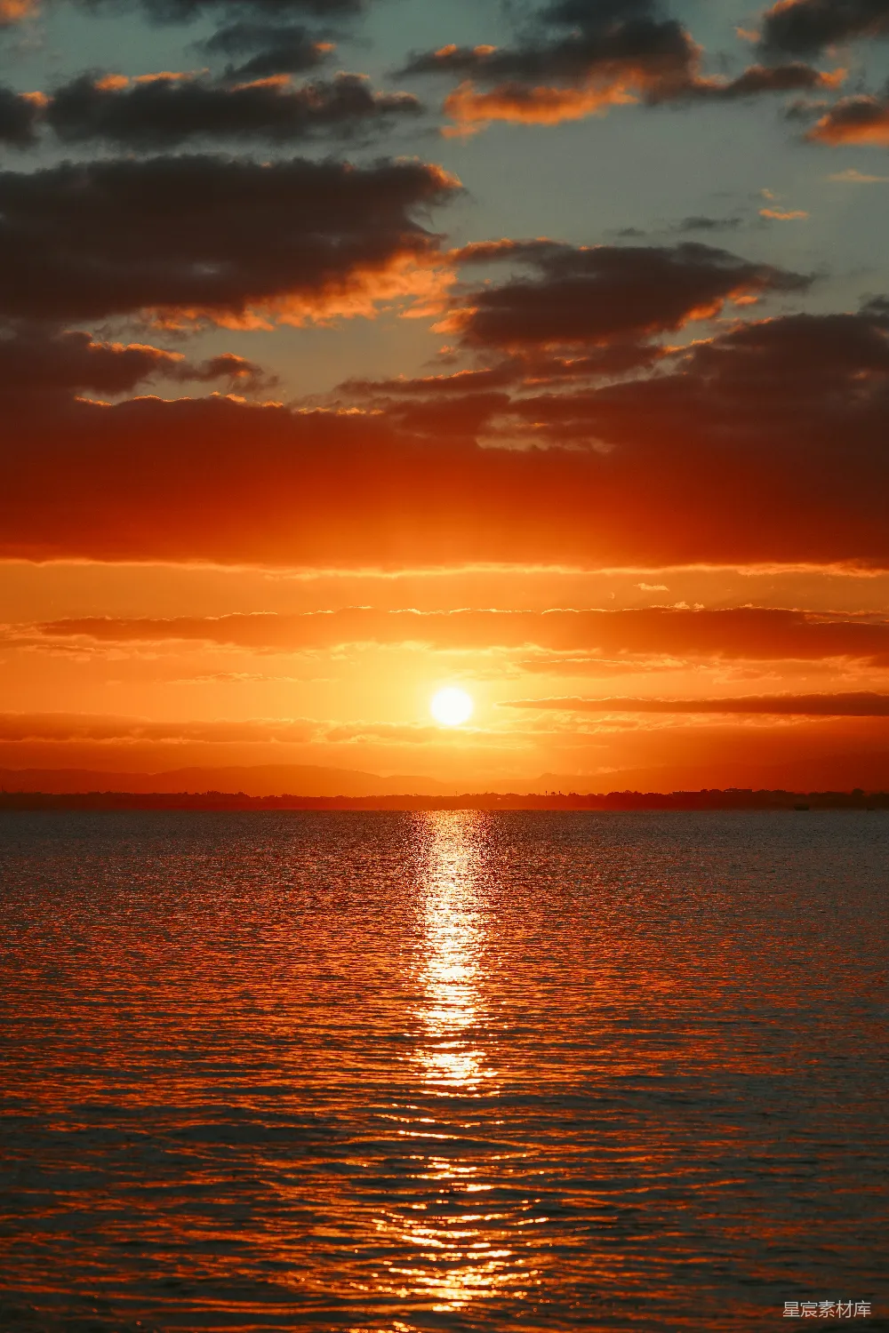 高清摄影 背景中有一处广阔的水域，夕阳西下。