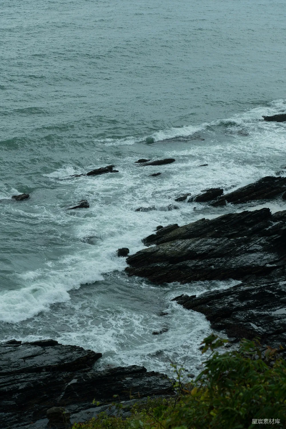 高清摄影 一块岩石嶙峋的海滩，海浪拍击著它。