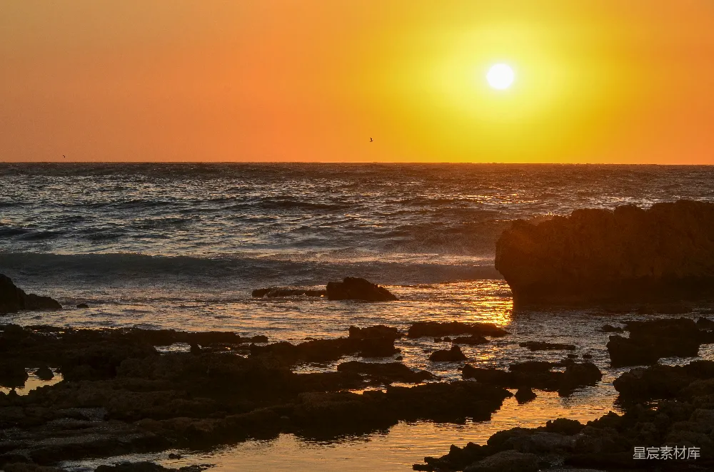 高清摄影  夕阳西下，海平面上有岩石在前景。