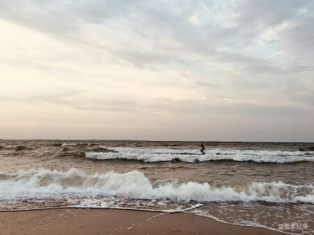 高清摄影  海洋中一个骑着冲浪板的人在波浪上。