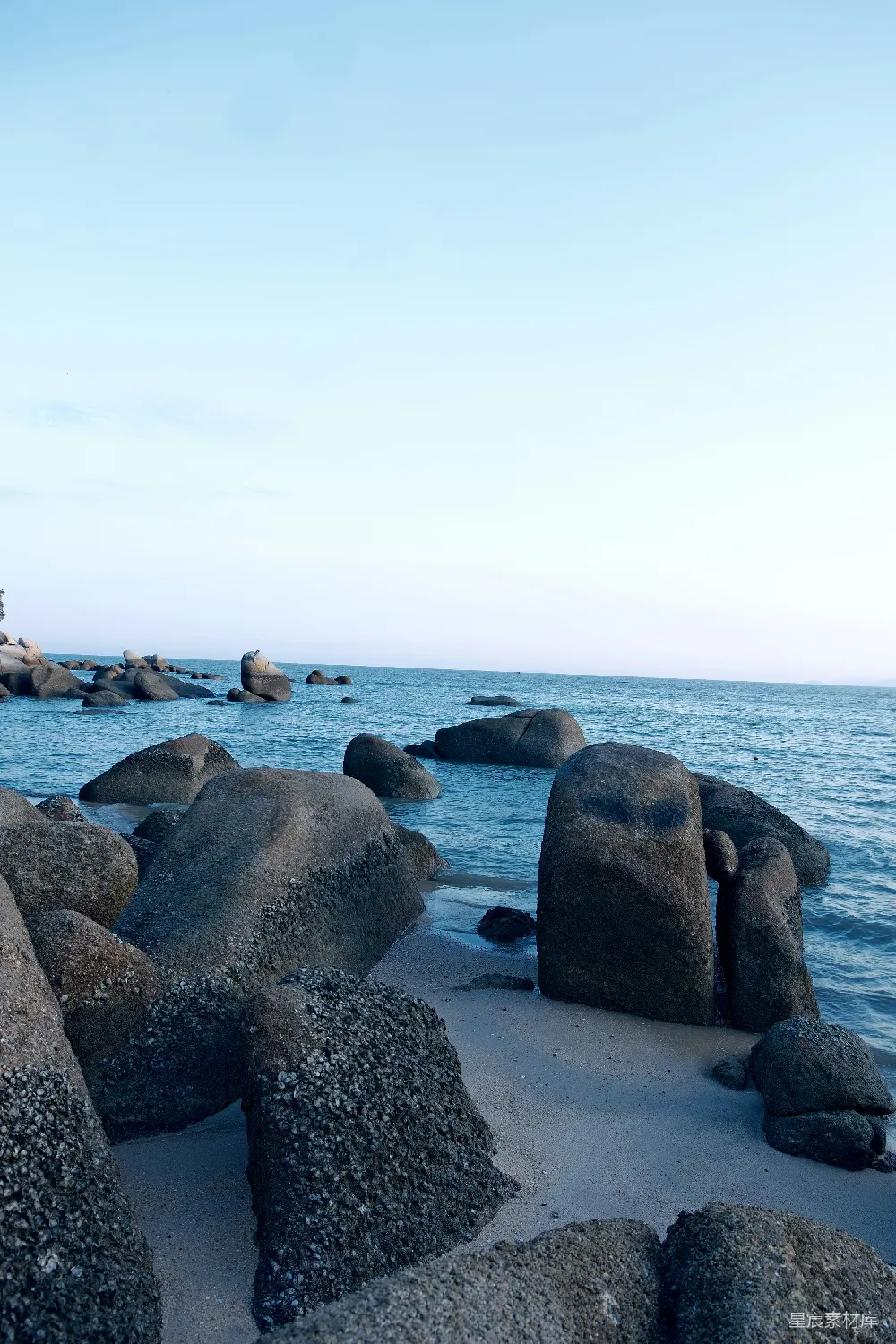 高清摄影 岩石嶙峋的海滩，水中有大石头。