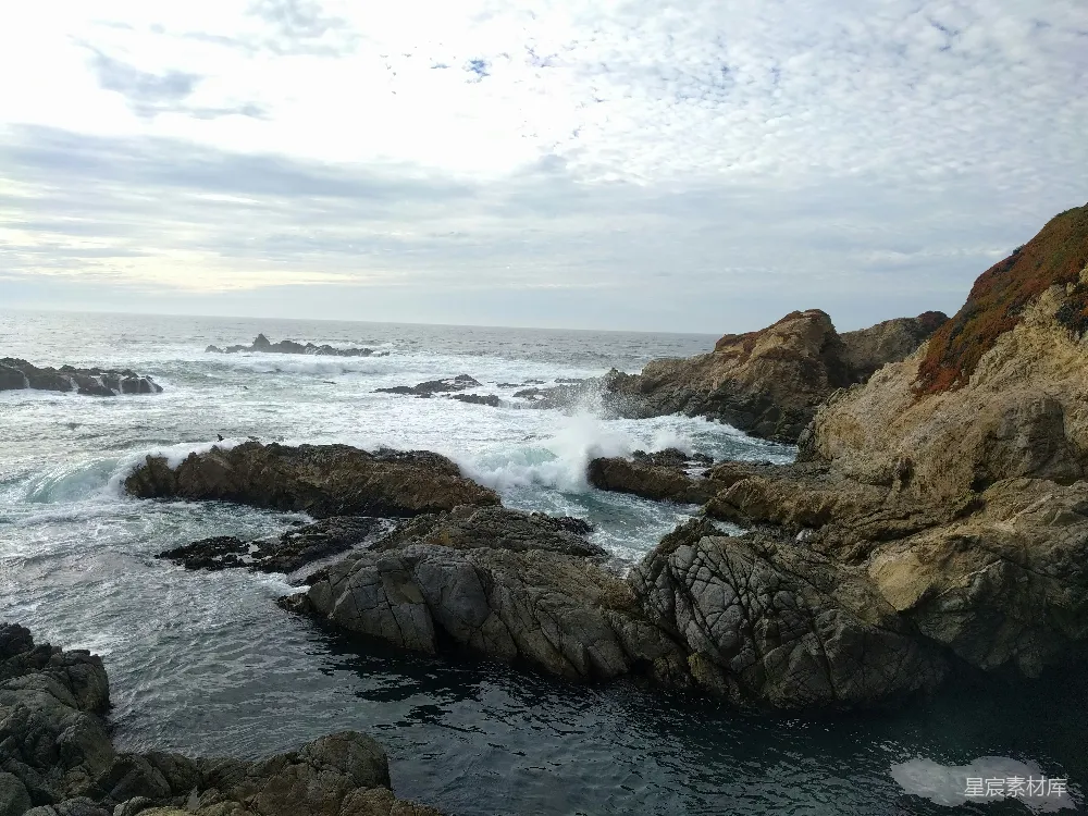 高清摄影 棕色的岩石海岸在白天的白云下被海浪覆盖