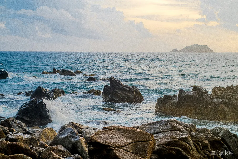 高清摄影 白天岩石海岸上有波浪，白云下阳光照射着。