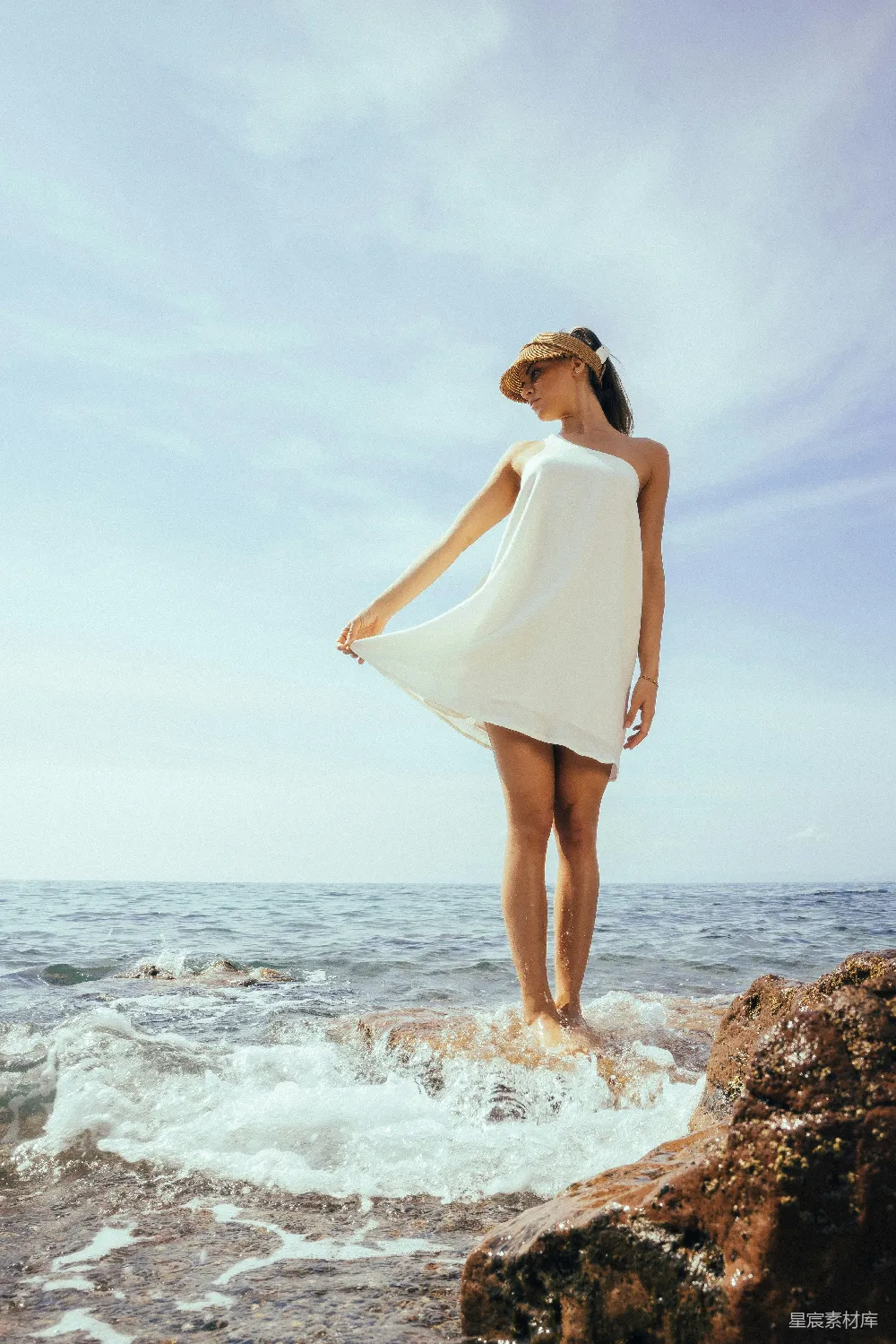 高清摄影 一个女人站在岩石上靠近海边。