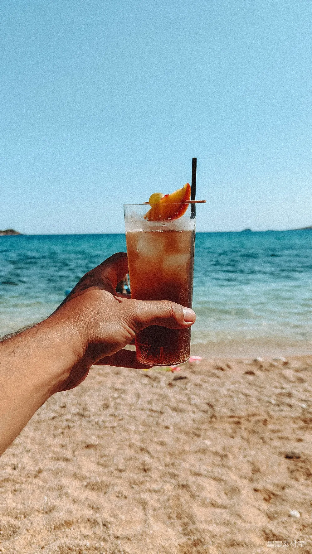 高清摄影 海滩上有人举着一杯酒。