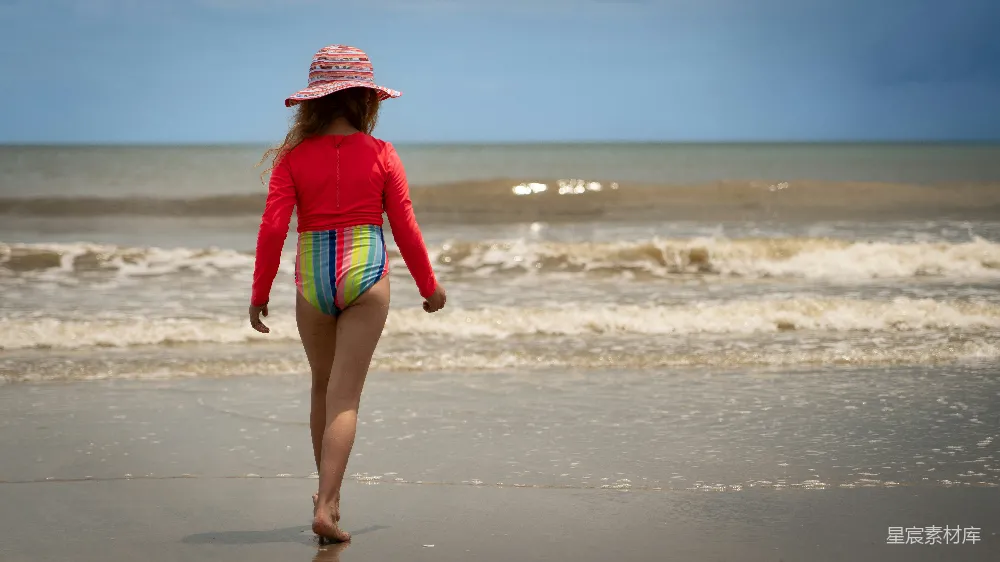 高清摄影 海边一位妇女在沙滩上行走靠近海洋