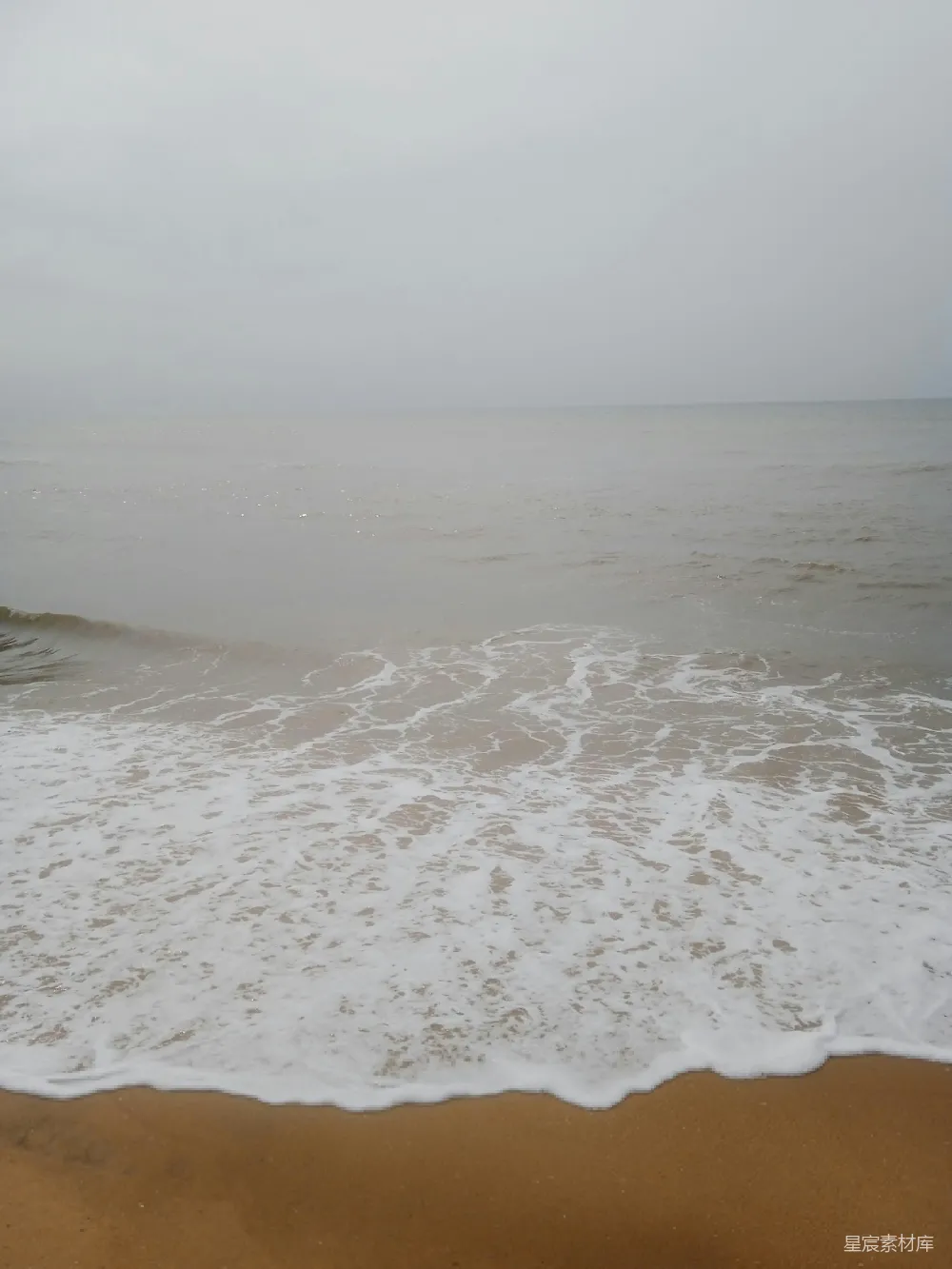 高清摄影 一片沙砾海滩，海浪涌向岸边