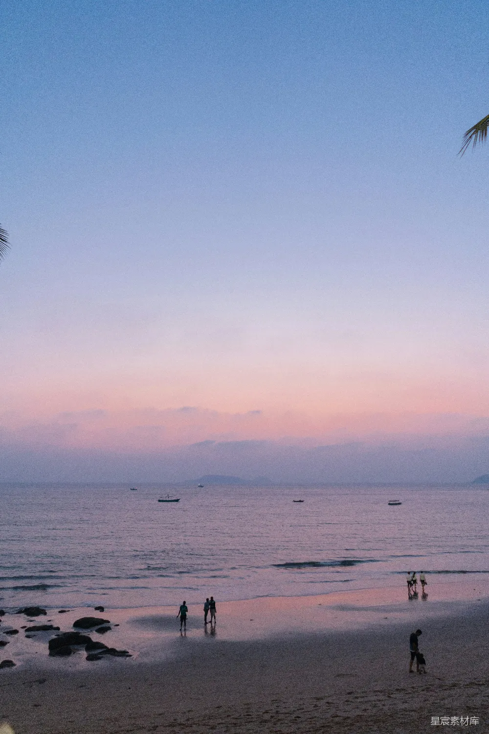 高清摄影 海滩上的人们在日落时分，海水平静。