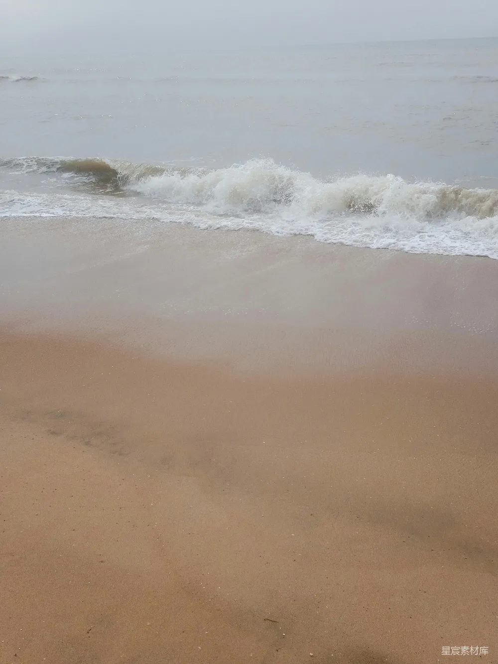 高清摄影 一片沙滩，海浪涌向岸边。