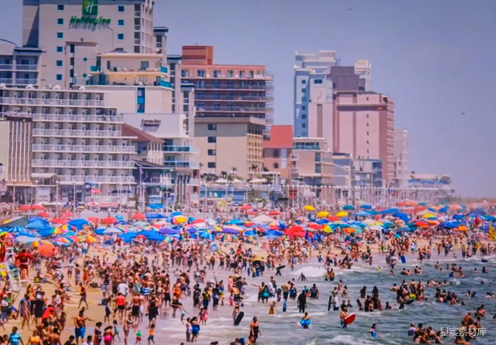 高清摄影 海滩上一群人的场景中，有遮阳伞。
