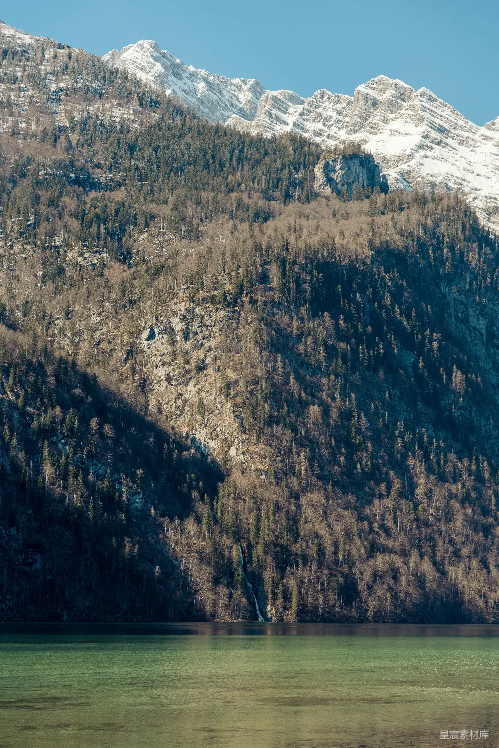 高清摄影 一座山顶被白雪覆盖的山脉旁边有一片水域