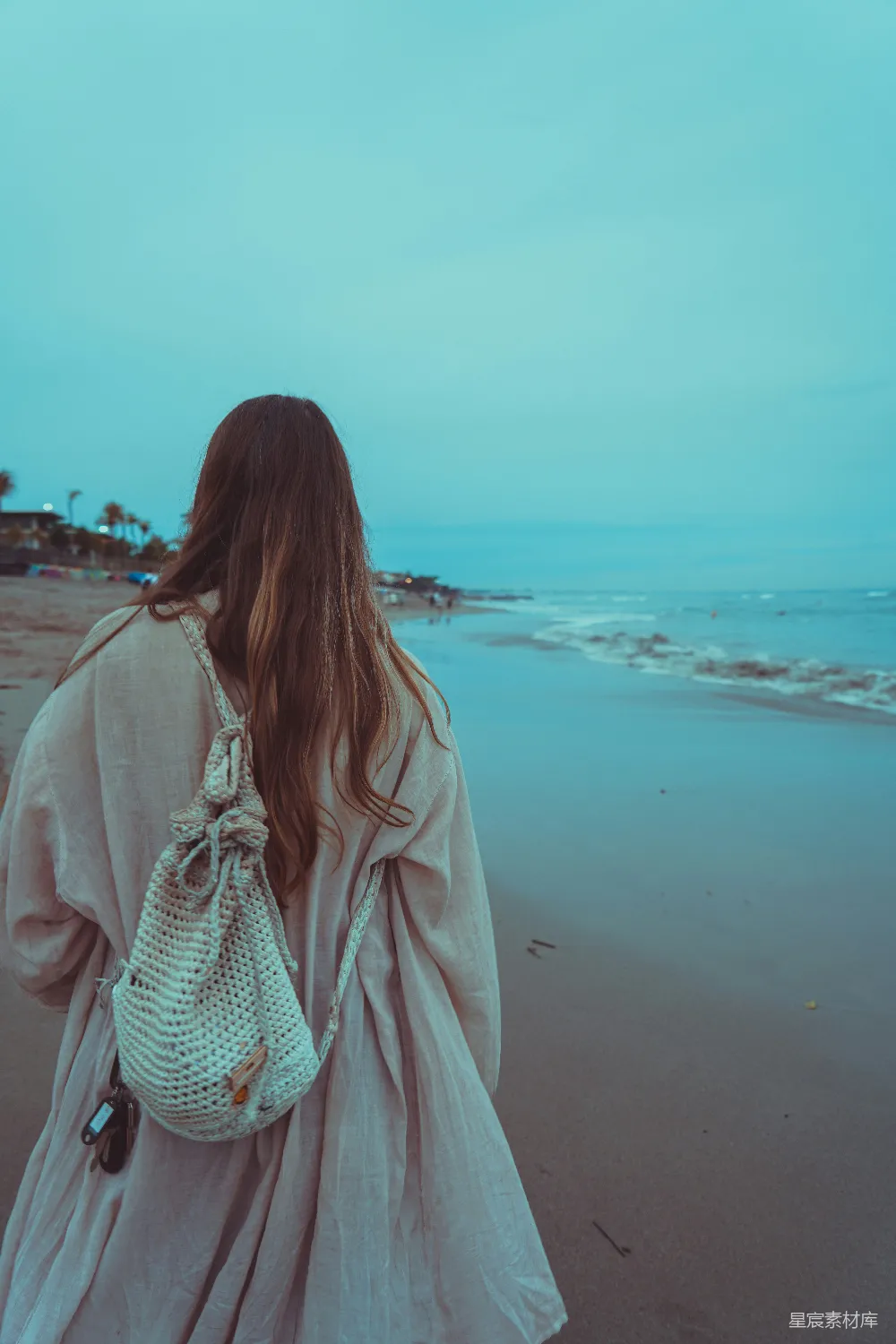 高清摄影  一个女人在海滩上拿着手提包散步。