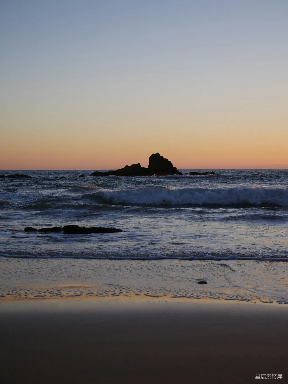高清摄影 夕阳西下，海面上有一座岩石在远处。