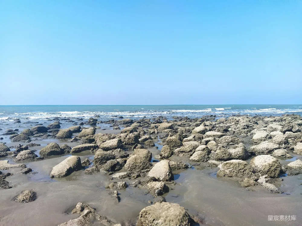 高清摄影  一片岩石海滩，水下是蓝天下的碧波