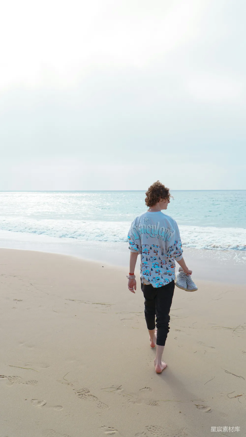 高清摄影 海滩上一个女人带着飞盘行走。