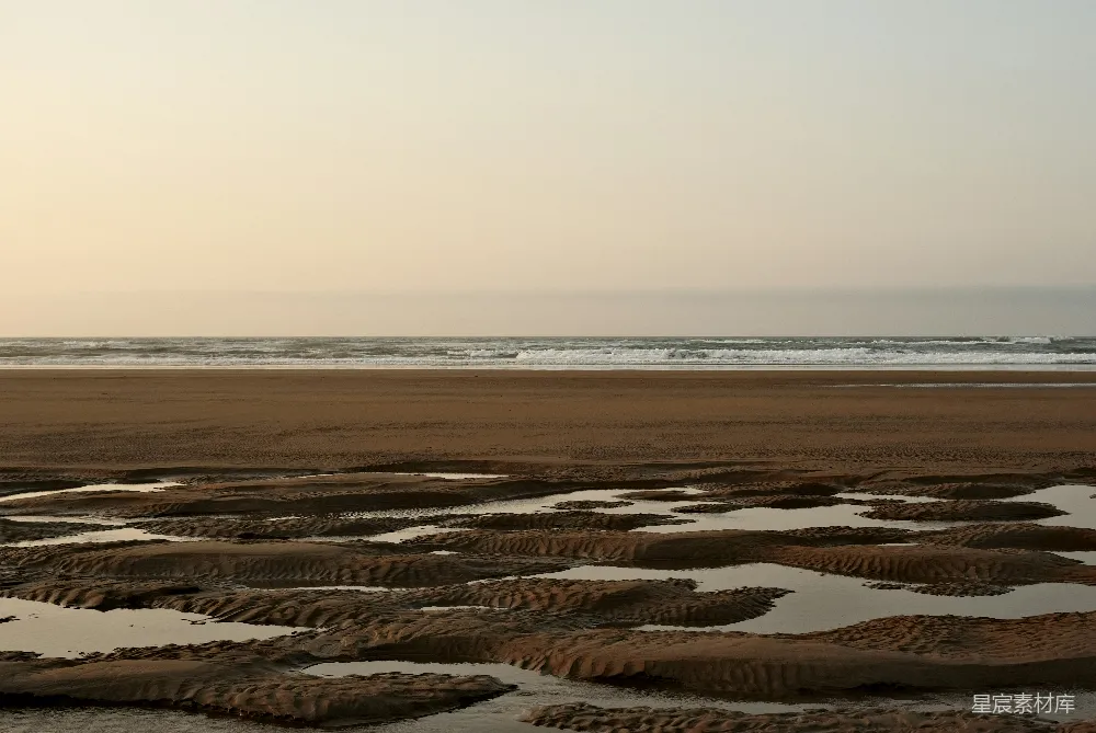 高清摄影 一片沙子铺就的海滩，海浪拍打著岸边