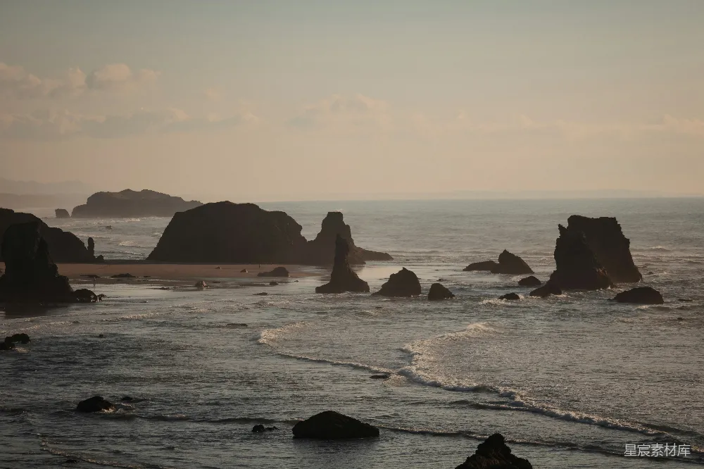 高清摄影 海边一块岩石嶙峋的海滩，在背景中有一片水面。